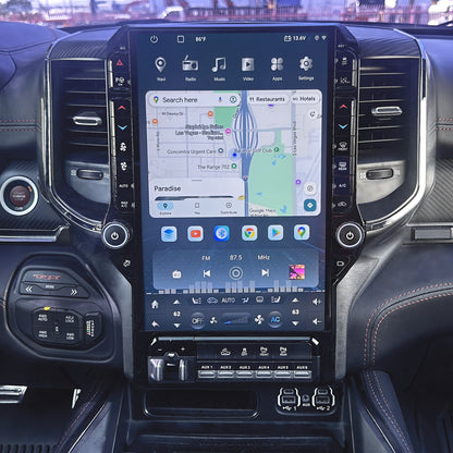 A large vertical touchscreen infotainment display mounted in the center of a car dashboard, showing a map and media controls. The surrounding cabin includes air vents, climate controls, and textured trim.